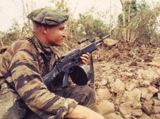 A tiger stripe clad SEAL team member in the Mekong Delta keeps guard with a Stoner 63A Commando during Operation Bold Dragon III.