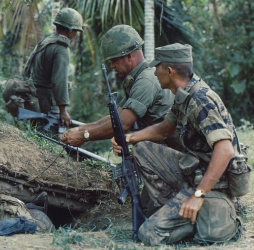 A 101st Airborne recon team member carries his M17 gas mask on his leg whilst inspecting a Viet Cong bunker complex during Operation Van Buren.