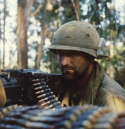 An M60 gunner of the 173rd Airborne Brigade carries a bottle of bug juice in his helmet band.
