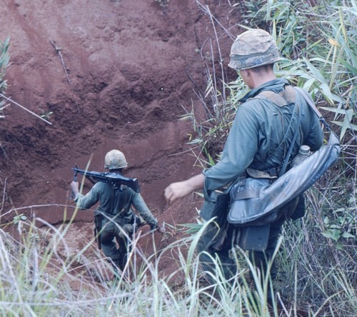 An M60 machine-gunner and his assistant gunner of the 22nd Infantry, 4th Infantry Division scramble down a bank whilst on a search and destroy near Pleiku in the Central Highlands.