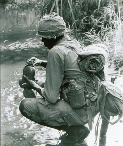 A member of the 2nd Battalion, 8th Infantry, 4th Infantry Division pauses to fill canteens from a stream during Operation Paul Revere IV.