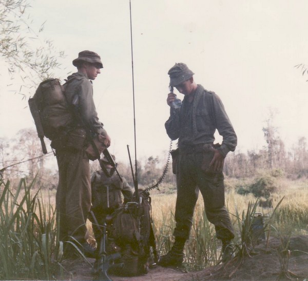 The executive officer of Company "D", 5th Battalion, Royal Australian Regiment, looks on whilst his radioman requests helicopter extraction.