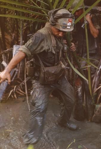 A soldier of the 47th Infantry, 9th Infantry Division uses his helmet band to keep a pair of socks and a pack of cigarettes 'high and dry' whilst wading a steam near My Tho in the Mekong Delta.