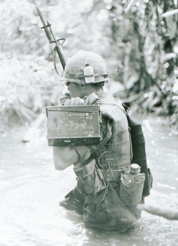 A soldier of Company B, 3rd Battalion, 60th Infantry, 9th Infantry Division carries an M60 ammunition can across a steam during Operation Sunflower in 1967.