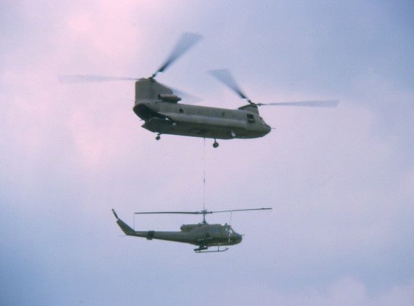 A CH-47 Chinook airlifts a damaged UH1-B Gunship of the 336th AHC out of Soc Trang.