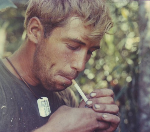 Sp4 John Davison wears his dog tags around his neck and lights a cigarette during a work break.