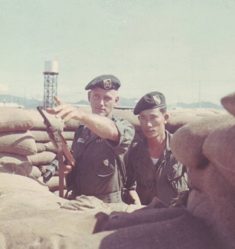 Captain Roger Donlon inspects a weapons emplacement at the Nam Dong CIDG camp with a member of the Vietnamese Special Forces.