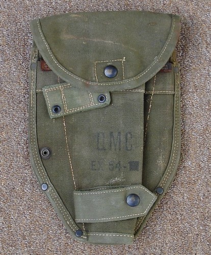 The EX-54 intrenching tool cover had male snap fastener on the left side that was used to secure a strap that wrapped behind the cover from the right.