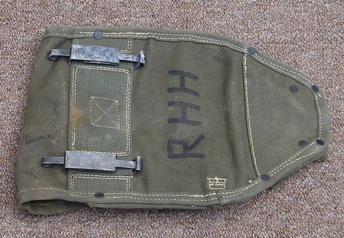 Early test versions of the EX-54 intrenching tool cover origianlly had a strap that wrapped behind the cover and mated with the snap fastener of the left side of the front.