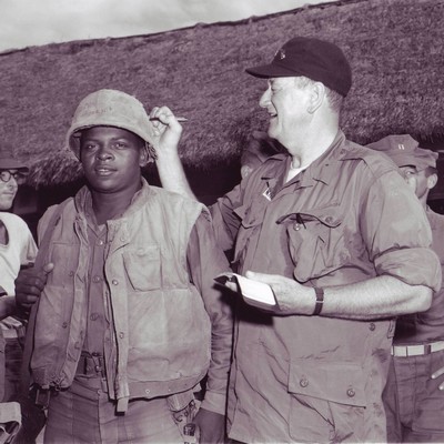 John Wayne signs PFC Wofford's helmet during his visit to the 3rd Bn.