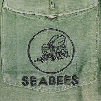 Subdued Seabees insignia directly embroidered onto the pocket of a fatigue shirt.